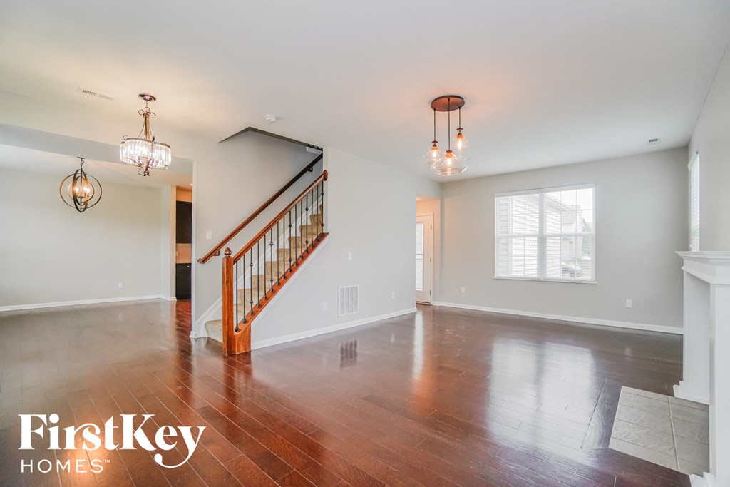 an empty living room with wood floors and a staircase
