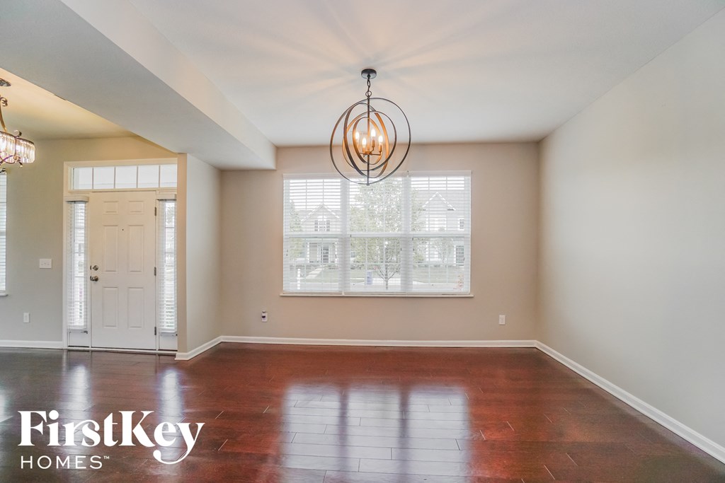 an empty dining room with a large window and a chandelier
