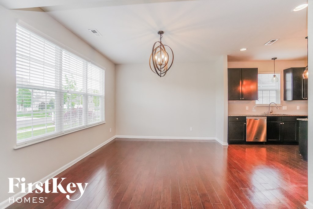 an empty living room and kitchen with wood floors and a large window