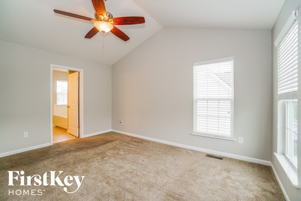 a living room with a ceiling fan and a carpet