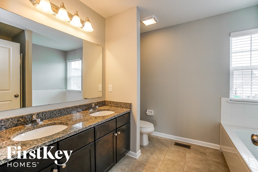 the master bathroom has dual sinks and a large mirror
