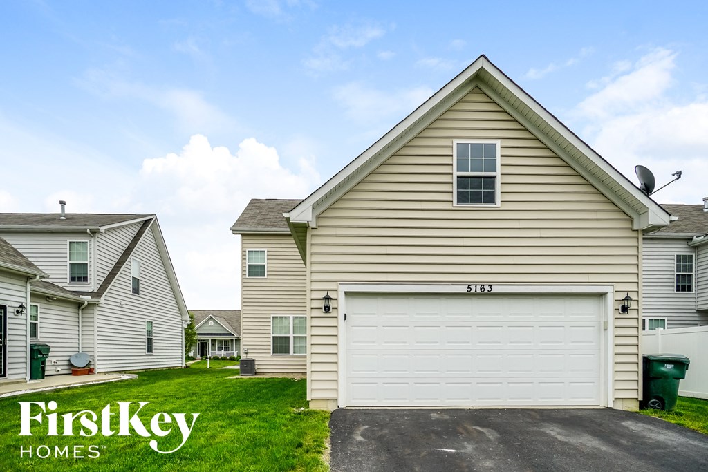 a house with a white garage door and a green lawn