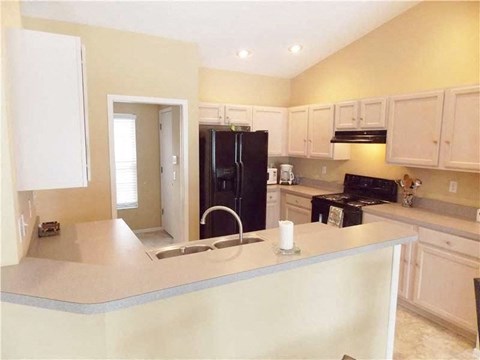 A kitchen with a black refrigerator and white cabinets.