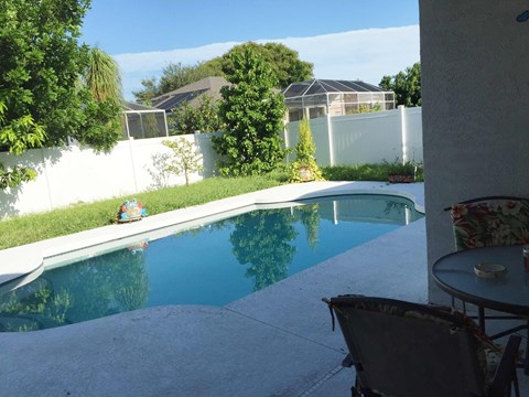 A person is sitting on a chair by a pool.