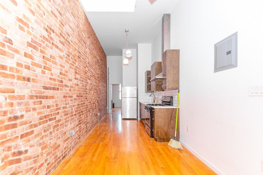 an empty room with a brick wall and a kitchen