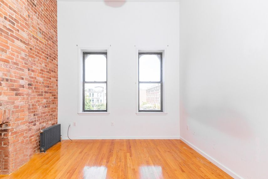an empty room with two windows and a wooden floor