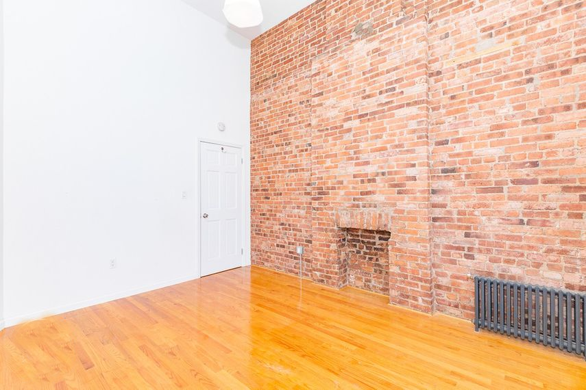 an empty room with a brick wall and wood floors