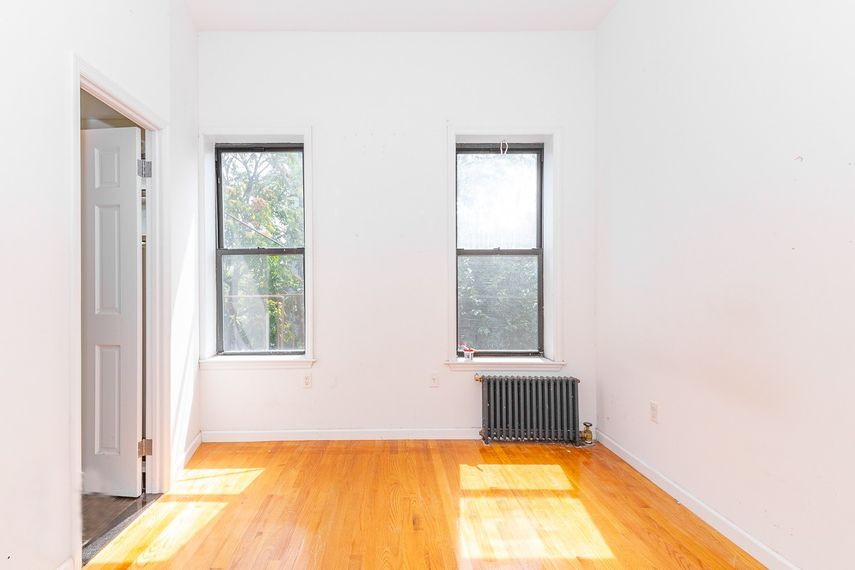 an empty room with two windows and a wood floor