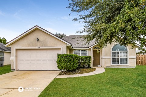a beige house with a white garage door and a lawn