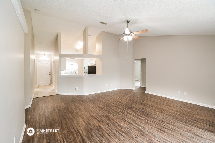 an empty living room with wood flooring and a ceiling fan