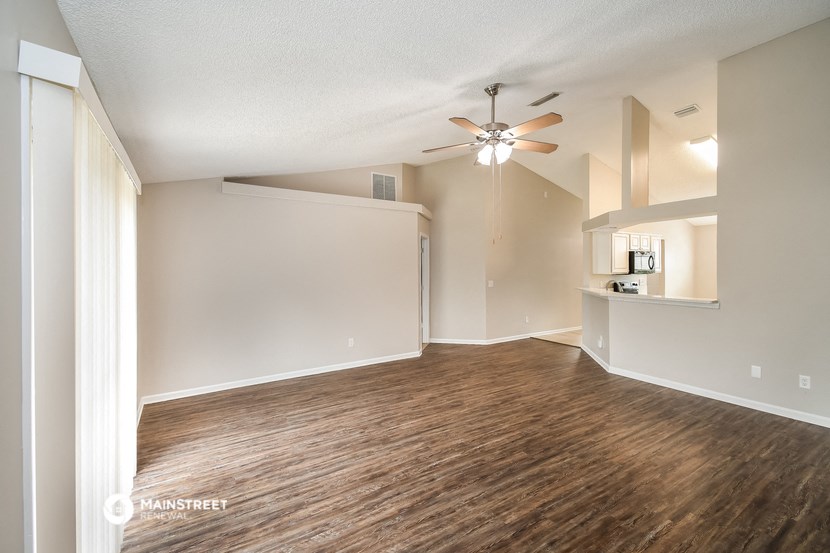 an empty living room with wood flooring and a ceiling fan