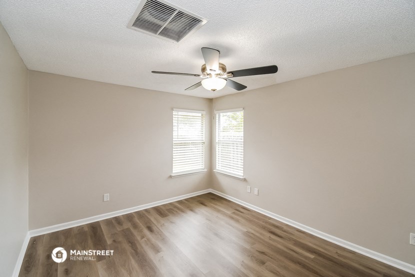 the spacious living room with ceiling fan and window