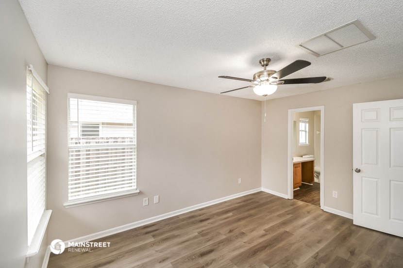 an empty living room with a ceiling fan and a window