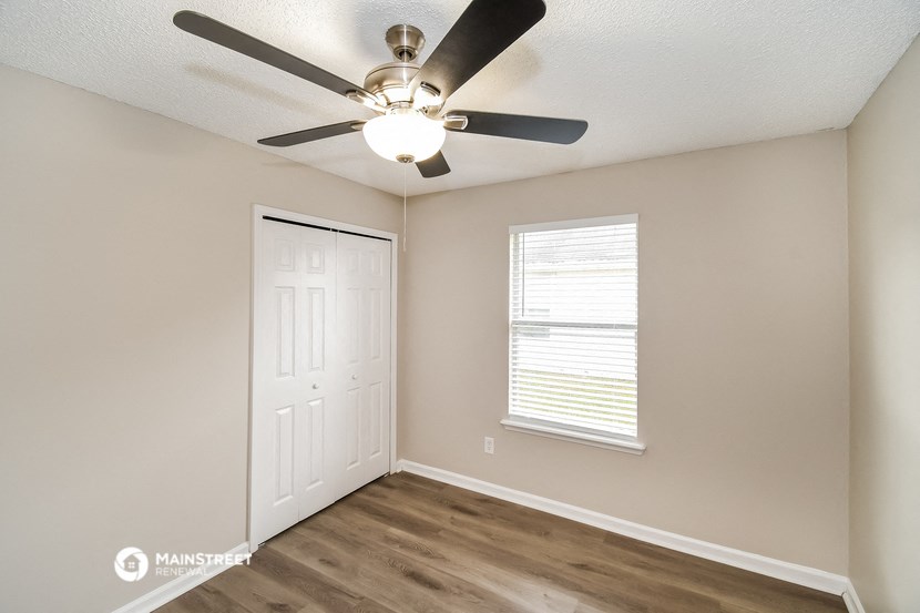 an empty bedroom with a ceiling fan and a closet