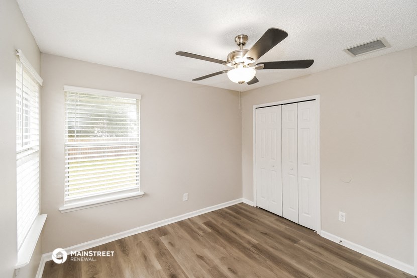 the spacious living room with a ceiling fan and a closet