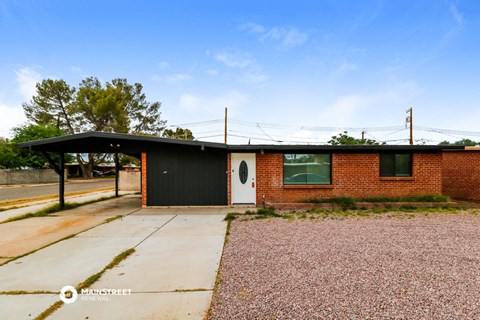 a small brick house with a black door and a driveway