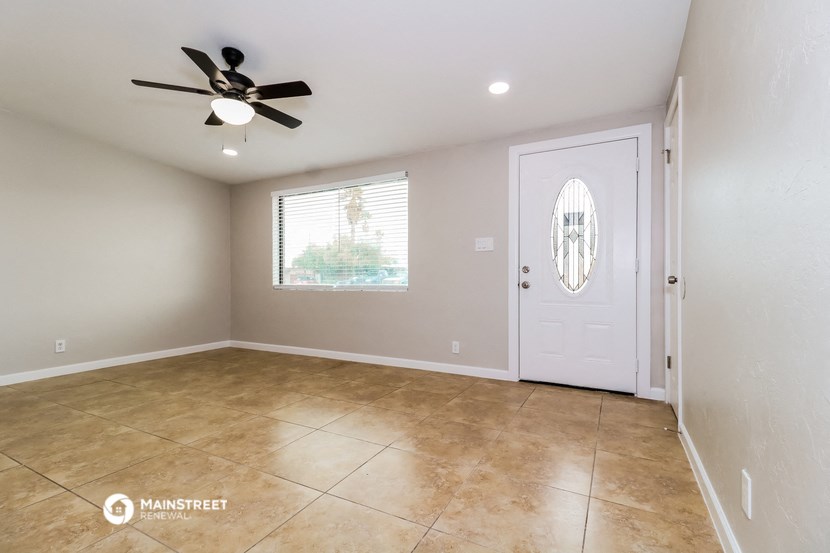 an empty living room with a ceiling fan and a white door