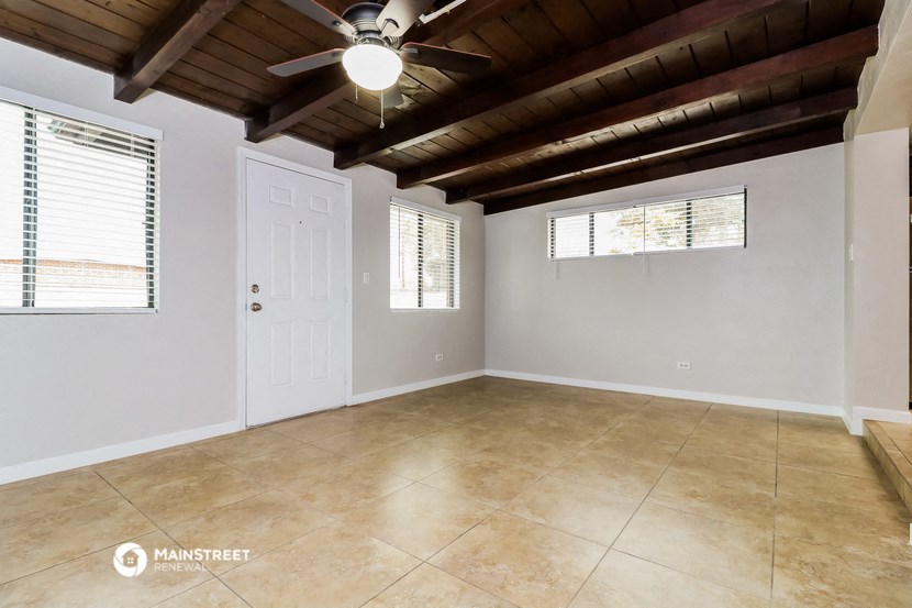 the empty living room of a house with a ceiling fan