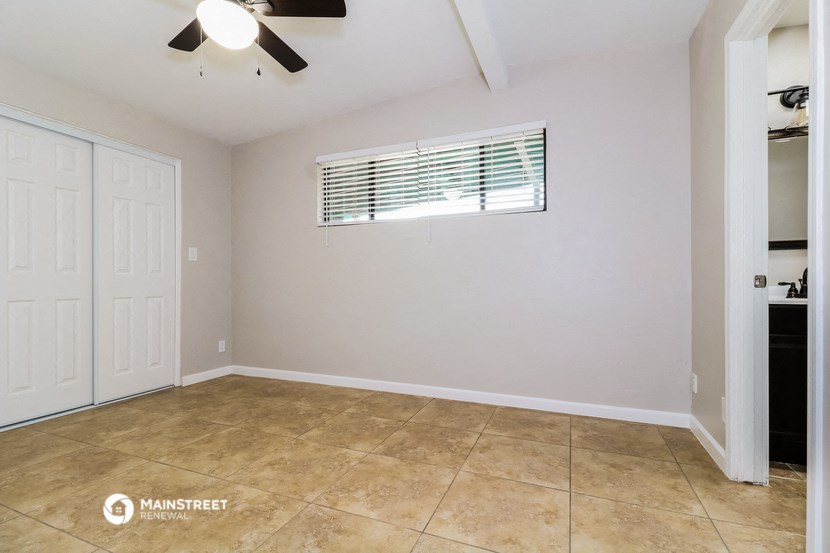 the living room of a home with a tile floor and a ceiling fan
