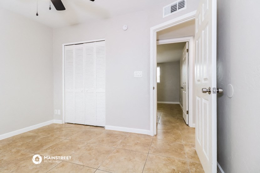 an empty room with a hallway to a closet and a door to a bathroom