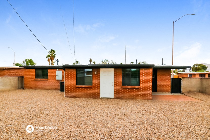 a small brick house in the middle of a dirt field