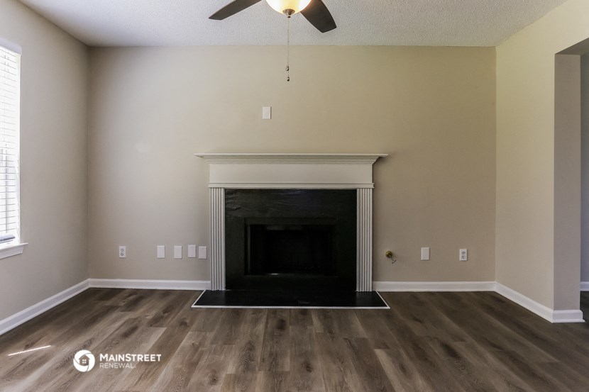 the living room with the fireplace and wood flooring