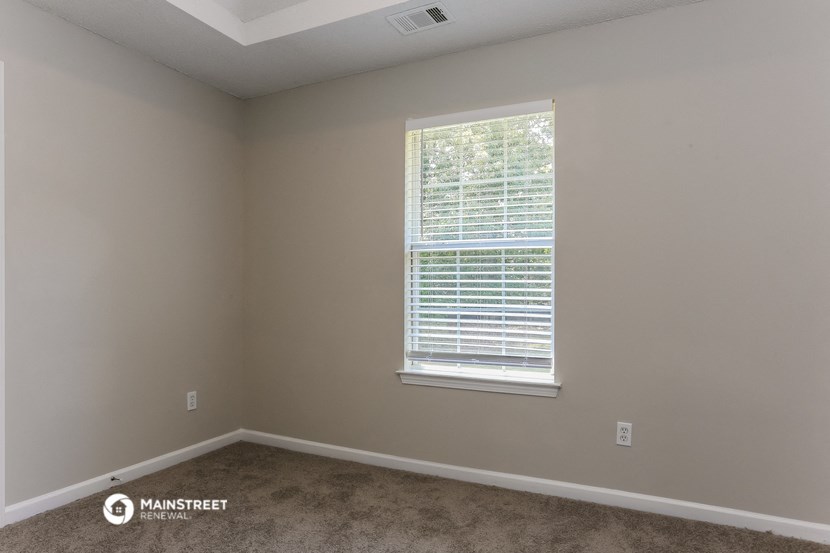 a bedroom with a window and a carpeted floor