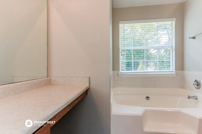 a bathroom with a tub and a sink and a window