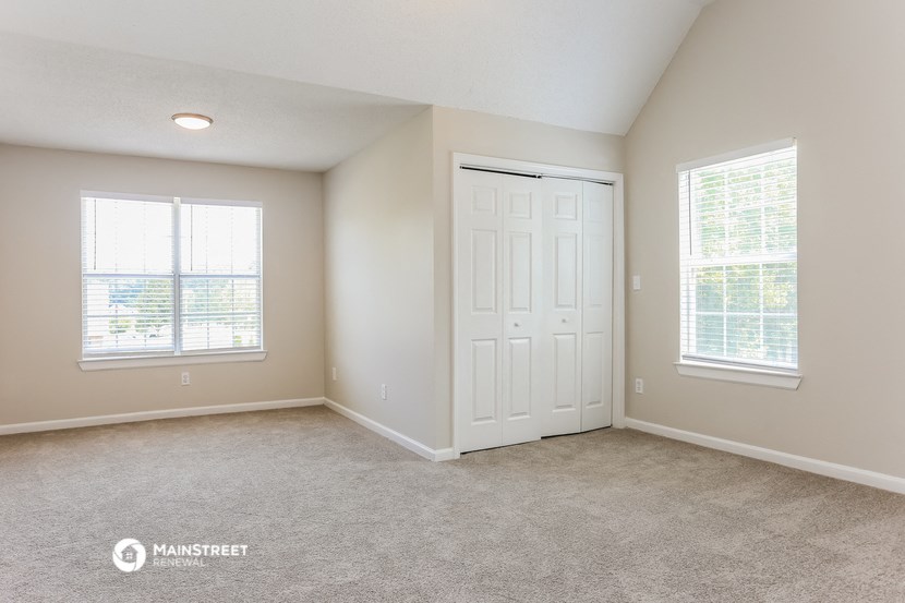 the spacious living room of a home with a white door and window