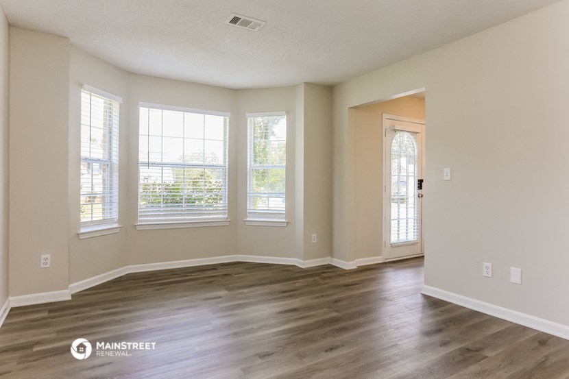 an empty living room with wood floors and windows