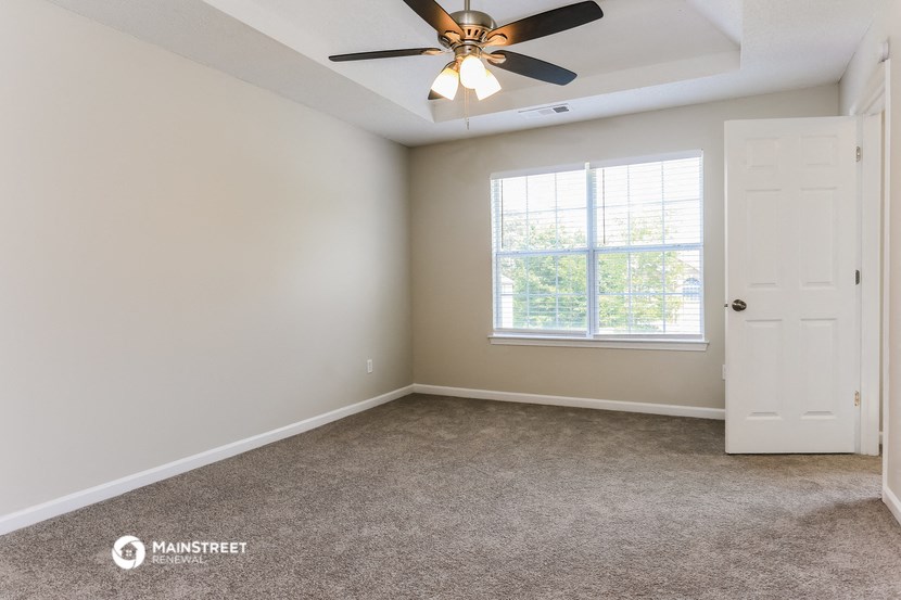 an empty room with a ceiling fan and a window