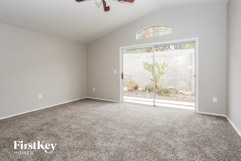 A room with a carpeted floor and a ceiling fan.