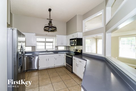 A kitchen with a stainless steel refrigerator and white cabinets.