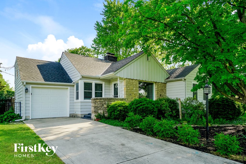 a white house with a driveway and a tree