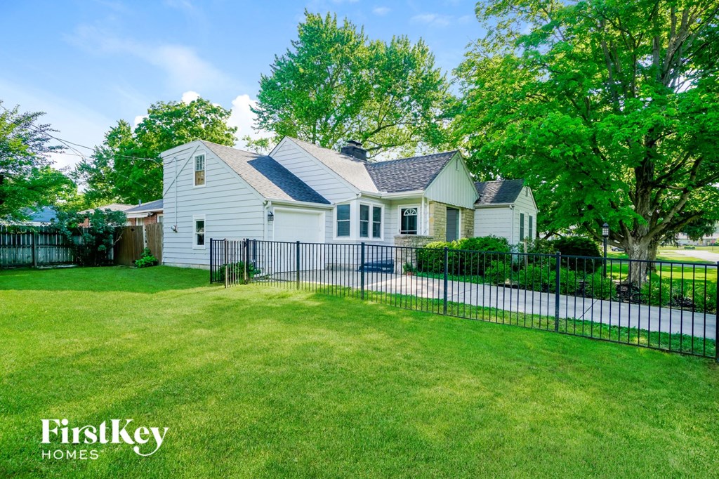 a white house with a black fence in front of a yard