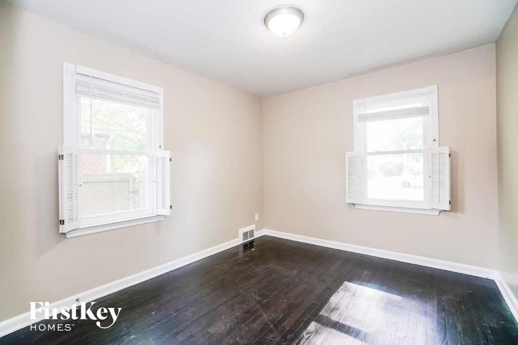 an empty room with hardwood floors and two windows