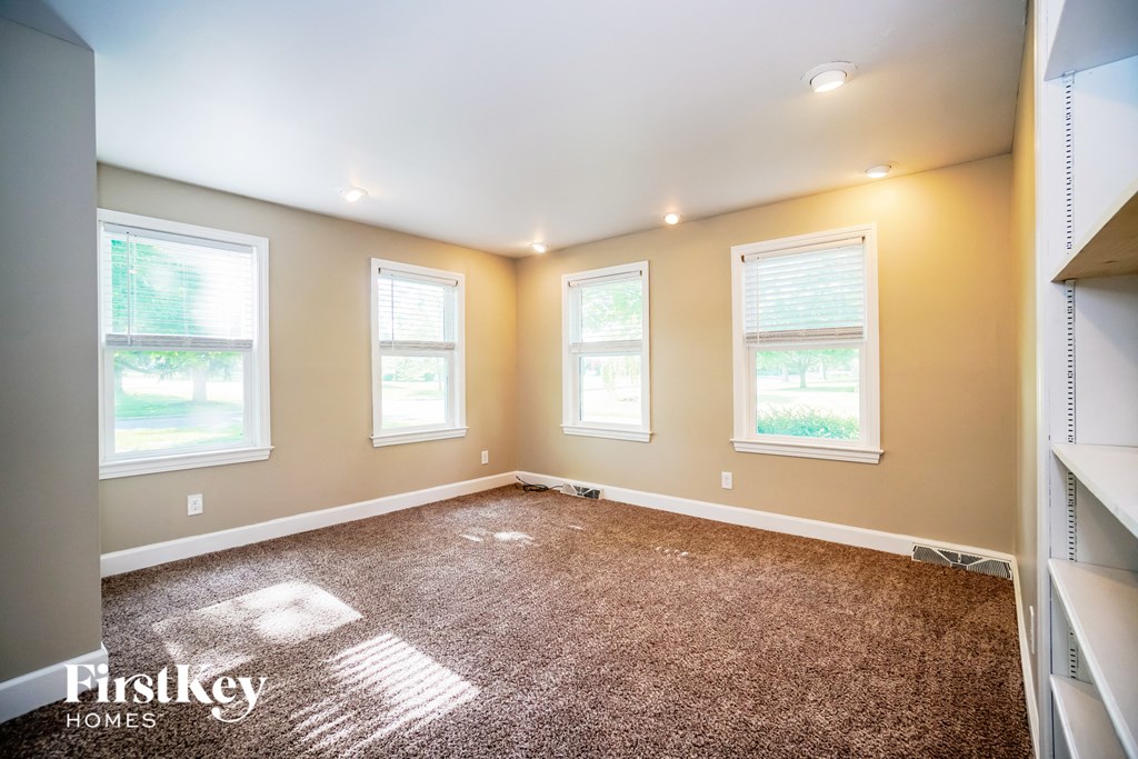 a bedroom with a carpeted floor and three windows