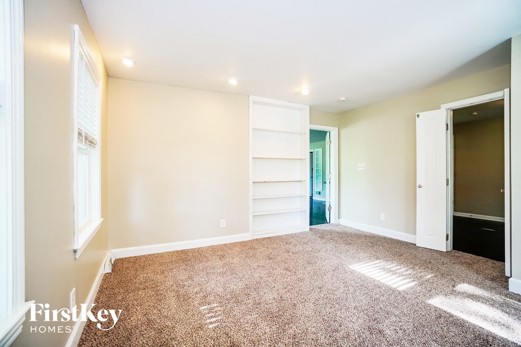 a living room with a carpeted floor and a door to a closet