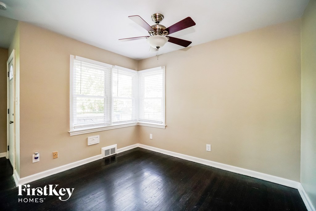 a empty room with dark wood floors and a ceiling fan