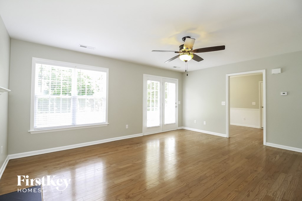 A room with a ceiling fan and wooden floors.