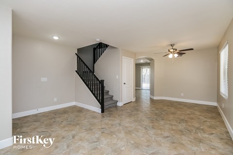 A spacious room with a staircase and a ceiling fan.