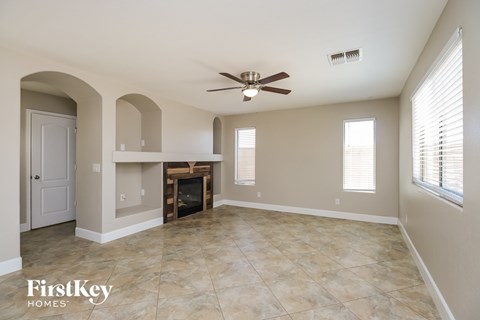 A spacious living room with a fireplace and a ceiling fan.