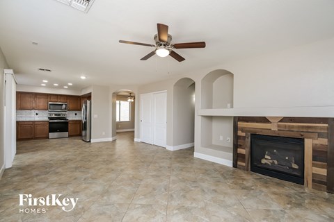 A spacious living room with a fireplace and a ceiling fan.