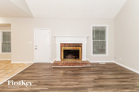 the living room with wood floors and a fireplace