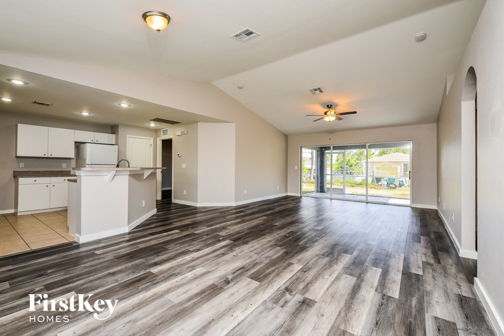 a living room and kitchen with wood flooring and a sliding glass door