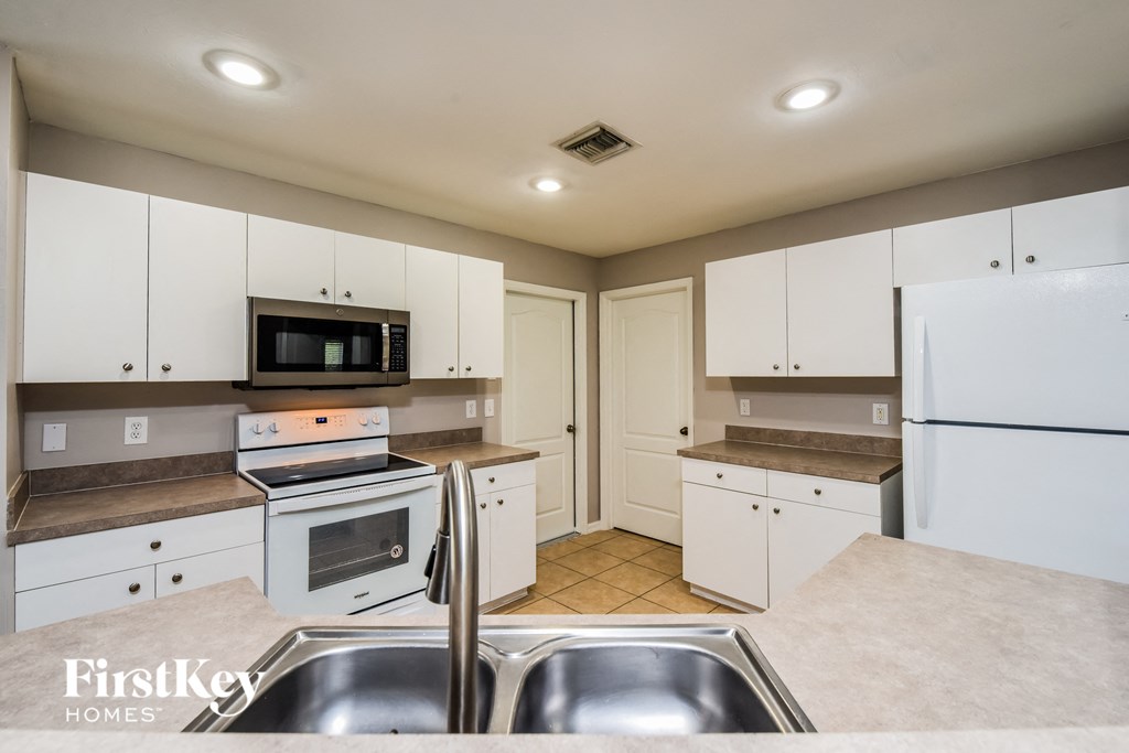 a kitchen with white cabinets and stainless steel appliances and a sink