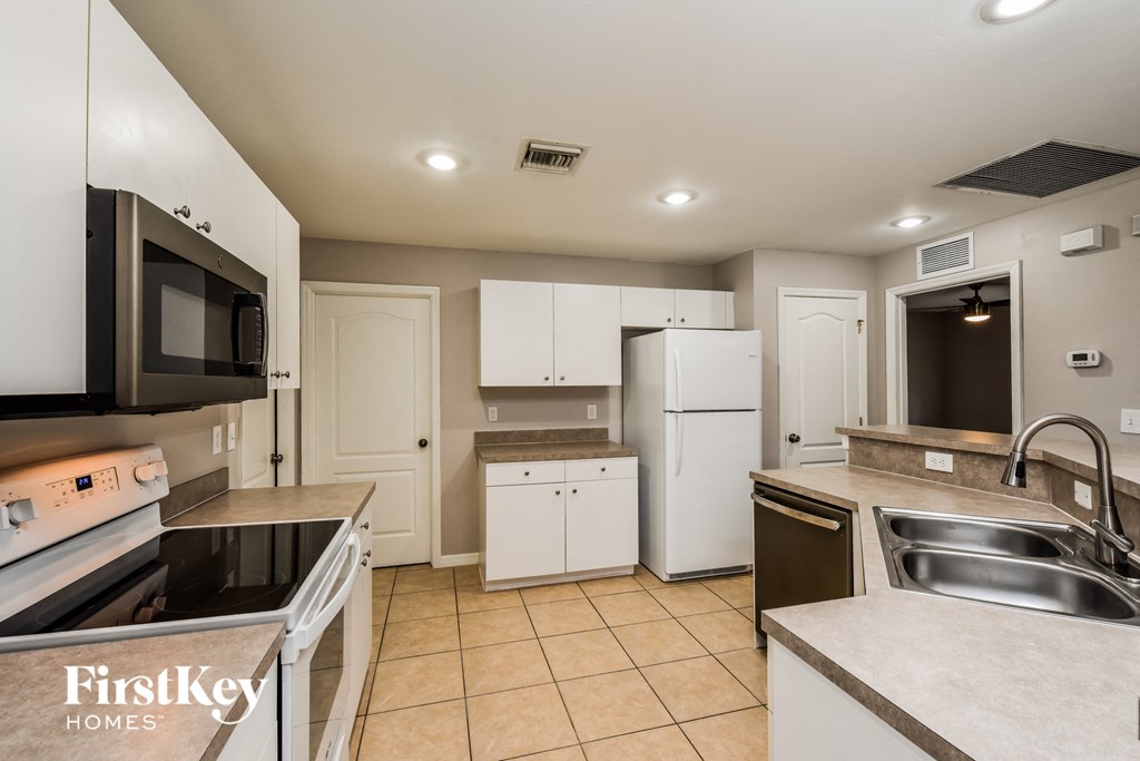 a kitchen with white cabinets and a sink and a refrigerator
