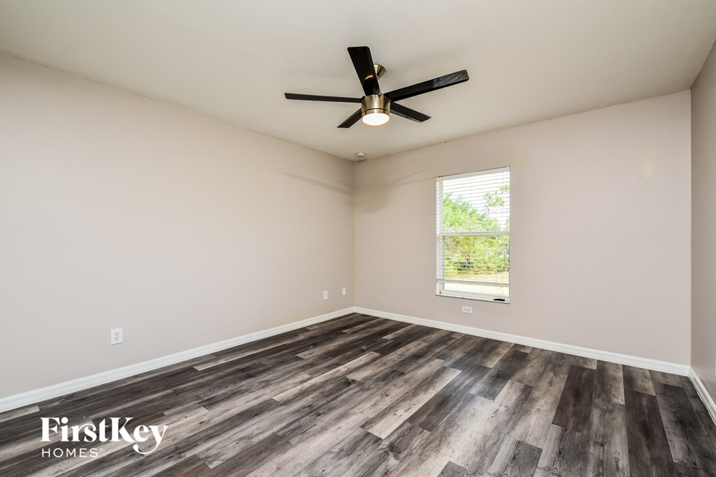 the spacious living room with wood flooring and a ceiling fan