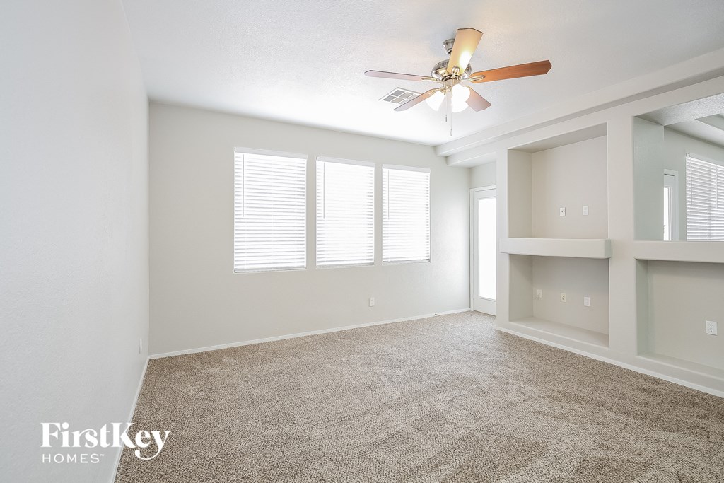 an empty living room with a ceiling fan and a window