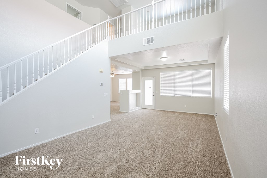 the living room and dining room of a white house with a white staircase and carpet